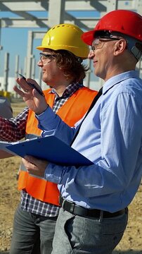 Cheerful Construction Team Discussing Project Progress on Future Factory Site. This vibrant footage highlights optimism, professional alignment, and modern industrial development.