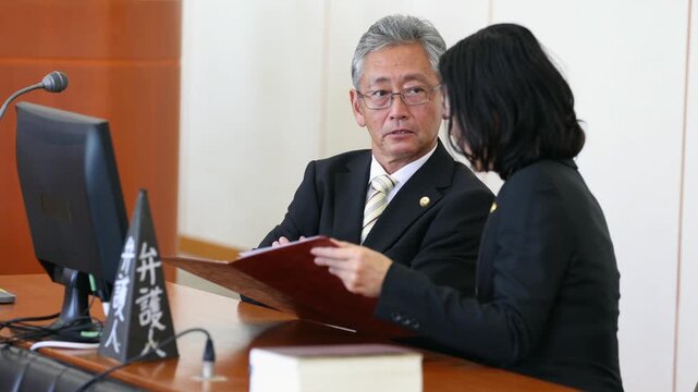 法廷で打ち合わせを行う男女の弁護士