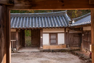 Fotobehang Bruin Looking Inside Through Wooden Gate Frame at Traditional Korean Hanok Courtyard and Buildings  © n3moh3ro