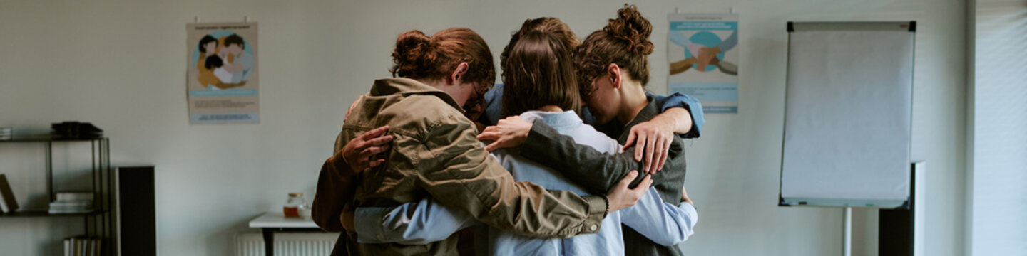 Header of diverse young adults embracing in support group therapy session, sharing comfort, trust, healing. Ideal for mental health, counseling, recovery, community care marketing