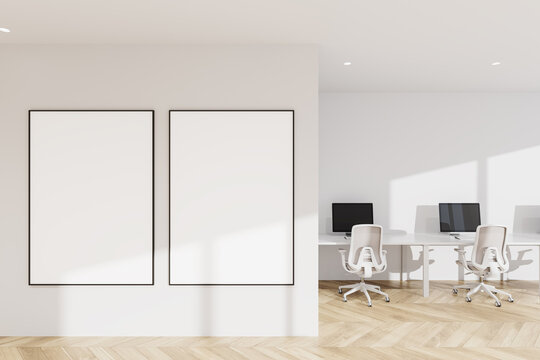 Minimal interior with two large blank poster mockup frames on a clean wall beside bright modern workspace in light office layout design template canvas wall picture light.. 3D Rendering