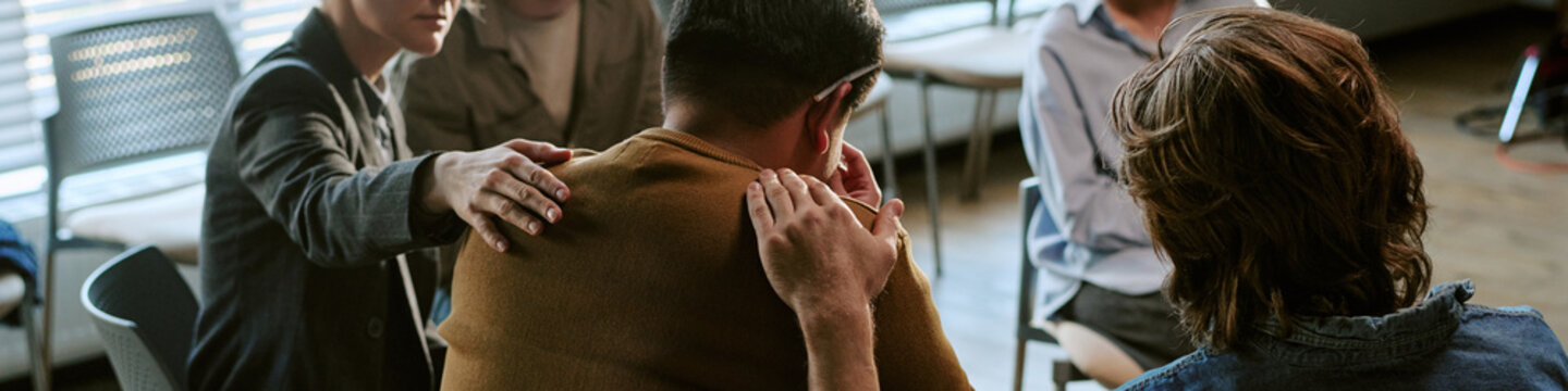Header of adults supporting young adult man during group therapy session, sharing comfort and emotional care for mental health recovery. Ideal for counseling, addiction recovery, wellness campaigns