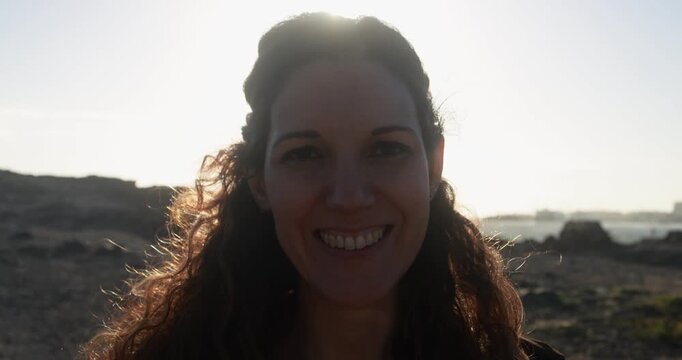 Happy woman smiling on camera during sunset time on the beach - Travel, holiday and lifestyle concept - UGC content