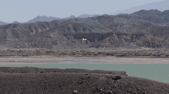 Drone tracks a large white bird flying above Cuesta del Viento Reservoir in Iglesia Department, San Juan Province, Argentina, with the arid Andes landscape and turquoise water below, drone tracking, h