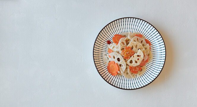 Lotus root and carrot salad with sesame on concrete background, top view