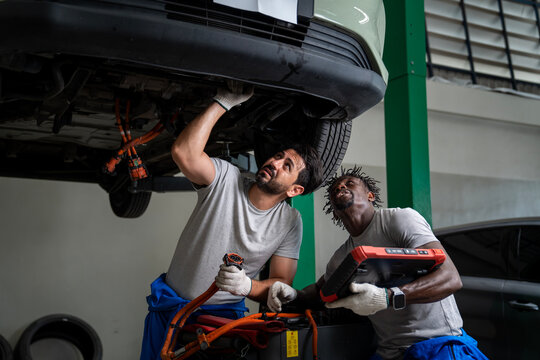 African mechanic and his team is wiring cable for ev car engine after annual check up in the professional garage and maintenance all the filter and gear for safety purpose