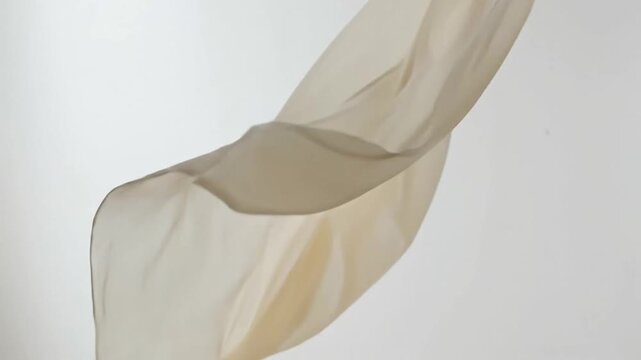 Elegant flowing beige fabric movement captured in slow motion showcasing smooth textures and graceful swirling patterns