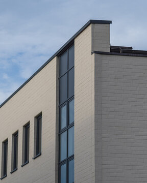 Building corner shows modern design and green leaves on a tree during daytime