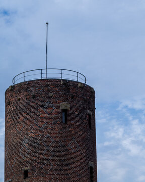 Historic brick tower stands under a blue sky with clouds at a public park in the afternoon