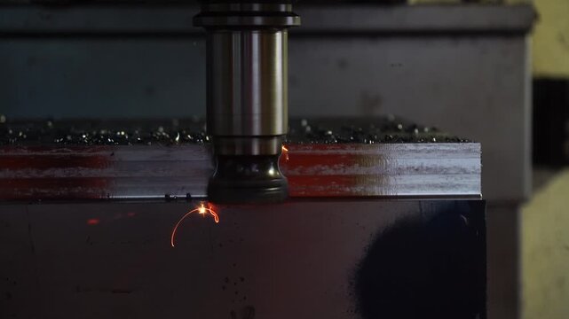 Red hot metal chips flying during CNC rough milling process with indexable insert tool.