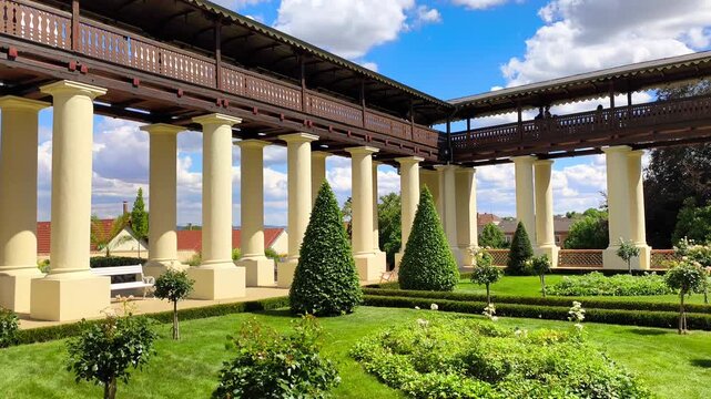 Beautiful colonnade with historic wooden walkway in a palace garden under a blue sky