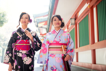 Two beautiful japanese women wearing traditional yukata clothing and going to the temple to...