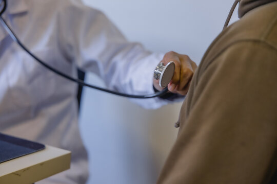 Doctor examining patient with stethoscope during routine medical checkup in a modern clinic. Healthcare, physical examination, preventive medicine