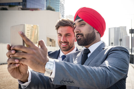 Multi-ethnic business team meeting outdoors, indian man taking a selfie with his colleague