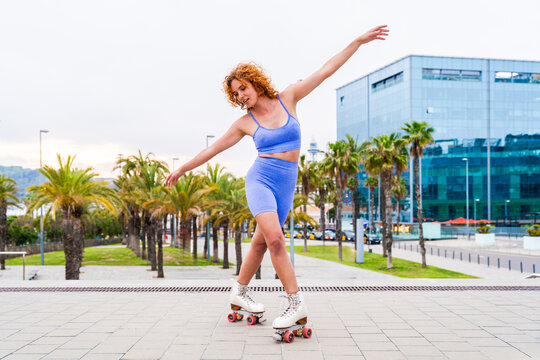 Beautiful red haired young woman with rollerskates having fun outdoors