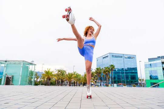 Beautiful red haired young woman with rollerskates having fun outdoors