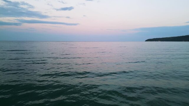 Tranquil Sea Sunset with Calm Waves and Coastal Silhouette