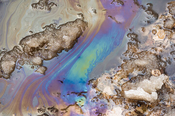 Obraz premium Iridescent oil slick on a road with melting snow, showcasing environmental pollution during springtime melt