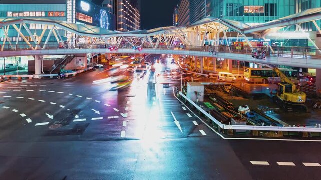 Osaka Intersection Timelapse Night Footage Showing Glowing Vehicle Light Trails Moving Through Urban Architecture and Modern Pedestrian Bridges Under Neon City Street Lighting 4k