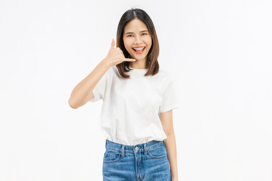 Happy young Asian woman making call me gesture on white background.