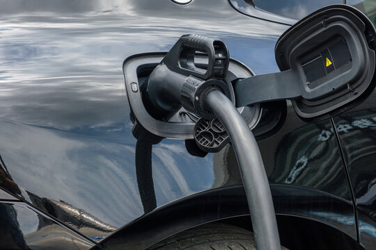 Electric vehicle charging plug connected to electric car at public charging station in Shenzhen city, China. Modern electric transportation, battery charging technology, renewable energy