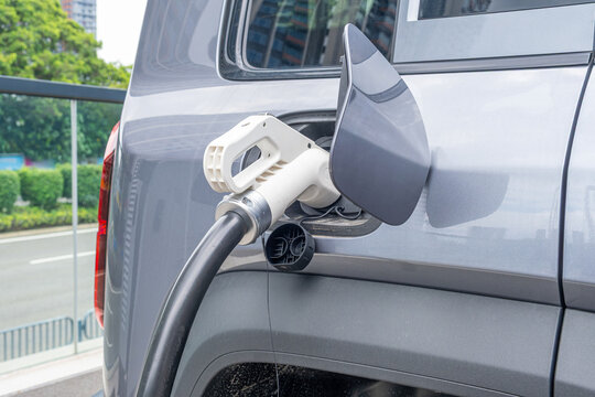 Close up of electric vehicle connected to charging cable during battery recharge, Shenzhen city, China. Clean EV transportation, sustainable energy solutions, electric mobility, modern technology