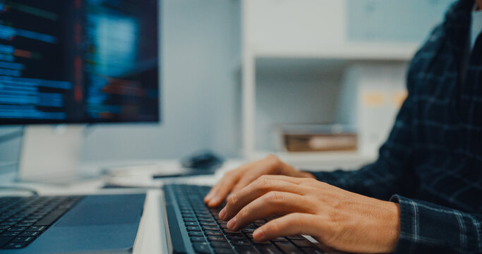 Close up young Caucasian male programmer writes code using multiple screens in home office workspace. AI development, cybersecurity, network database system, software engineering, remote tech startup.