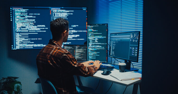 Young Caucasian male programmer write code on computer in home office at late night. AI technology, cybersecurity, software developer, freelance innovation, database system, digital network concept.