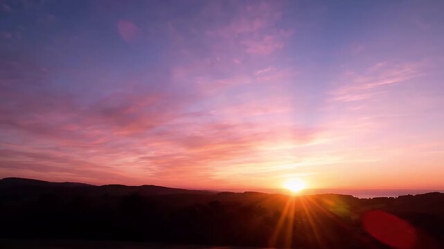 Beautiful Gradient Sunset Sky Over Silhouetted Hills - A stunning sunset displays a vibrant gradient of colors, transitioning from deep blue and purple in the sky to bright pink and orange hues as