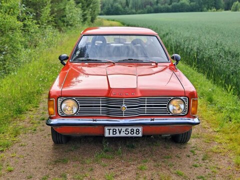 Red vintage Ford Taunus driving rural gravel path