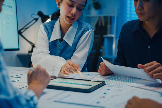 Close up asia businesspeople meeting plan analysis statistics brainstorm and tablet point graph chart employee take note in office conference room at night. Business finance partners strategy success.