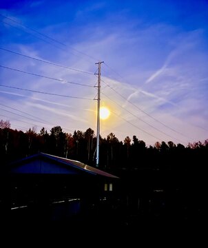 Full moon glowing over the Cheboygan River, through power lines.  Cheboygan, Michigan