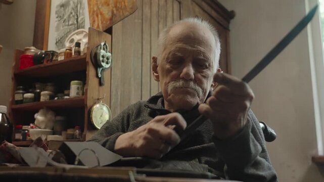 Elderly craftsman working in his old workshop, carefully restoring collectible Japanese bladed weapons