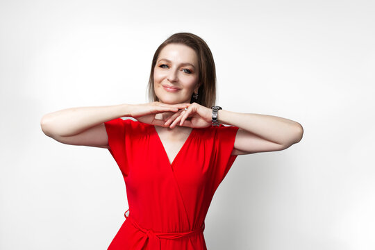 Young happy girl in red dress with hands under chin. Isolated on white background.