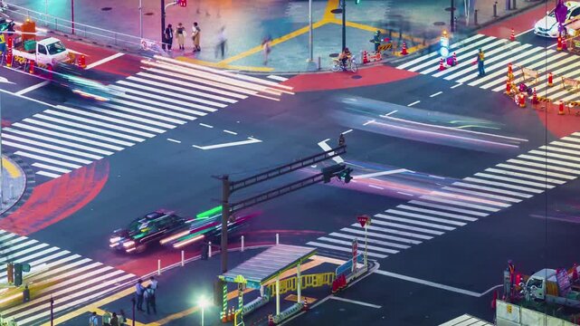 Timelapse Aerial View of a Bustling Urban Intersection with Motion Blurred Vehicle Light Trails and Pedestrians Moving Across a Busy City Street Junction at Night 4k Video