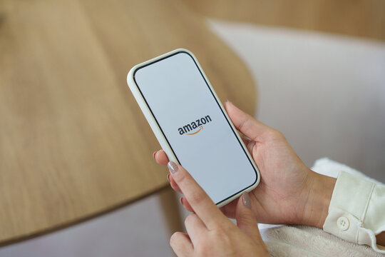 Woman holding iPhone 17 with Internet shopping service Amazon
