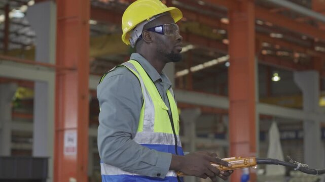 A foreman, or factory worker, is using a remote control to operate machinery in the factory.