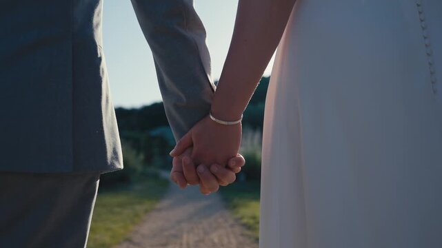 Bride and Groom Holding Hands on Garden Path at Sunset