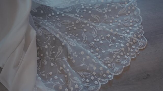 Close Up of Elegant Lace Wedding Dress Train on Wooden Floor
