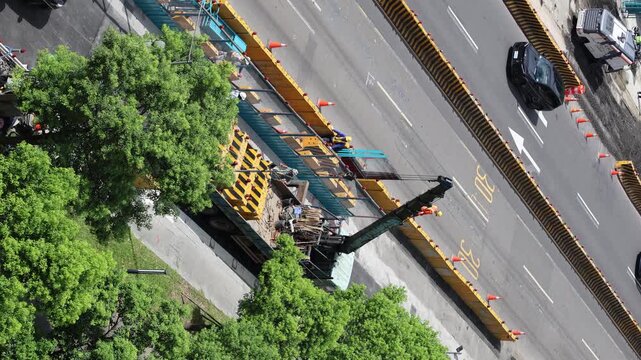 High angle view of urban road construction site with passing traffic on sunny day, 4K b-roll