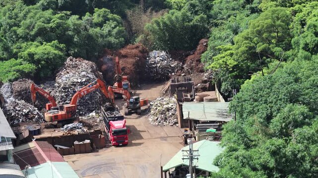 Aerial view of excavators sorting scrap metal in a recycling yard, 4K b-roll