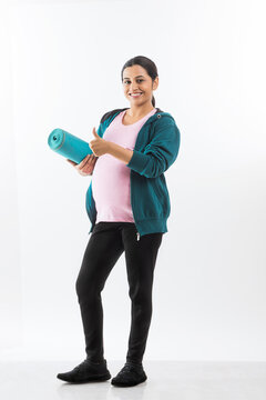 Pregnant woman holding a yoga mat in hand. 