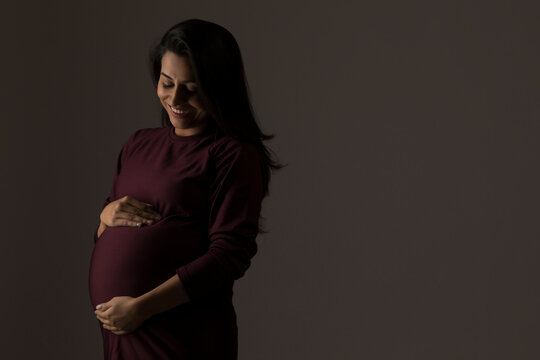 Pregnant woman holding her baby bump in anticipation. 