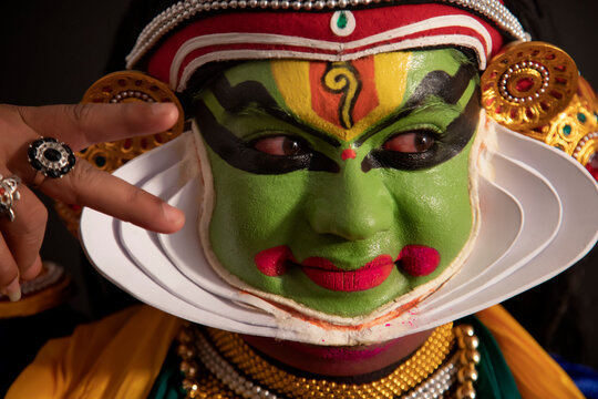 Kathakali dancer giving eye expressions with a smile on his face during a performance. 