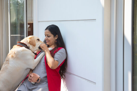 Woman sitting in the balcony and giving treats to her dog. 