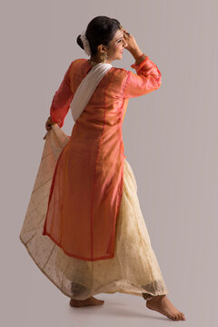 Kathak dancer performing gracefully over a plain background. 