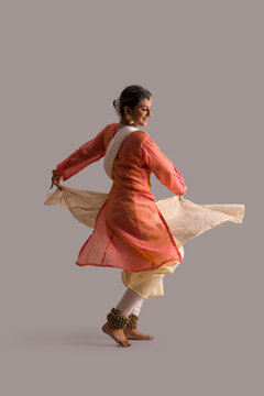 Gorgeous kathak dancer circling in front of a plain background. 