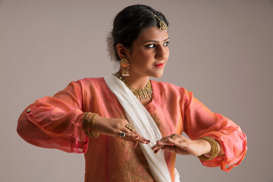 Beautiful kathak dancer performing through her expressions over a plain background. 