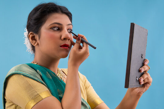 Kathak dancer applying eyeliner on her eyes. 