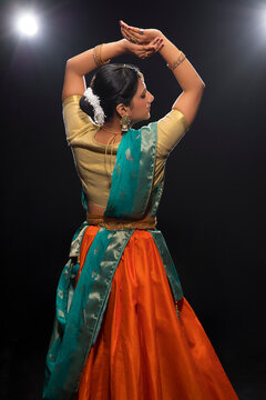 Kathak dancer giving a mesmerising performing in front of a dark background. 